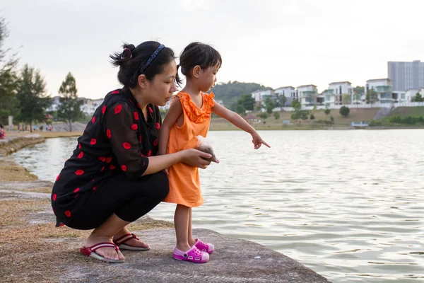 Asya anne ve kızı balık besleme — Stok fotoğraf