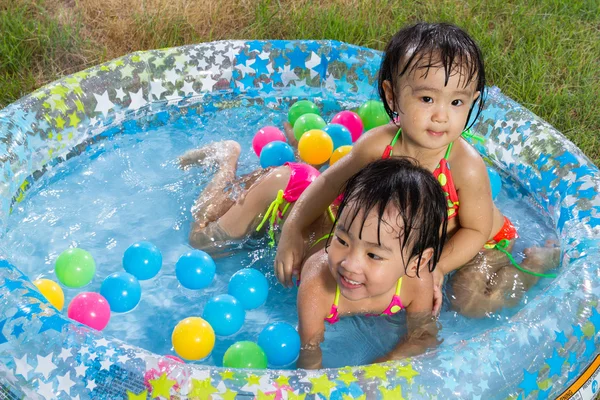 Asiática poco chino niñas jugando en un inflable goma nadando — Foto de Stock