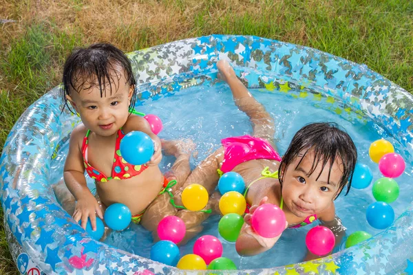 Asiática poco chino niñas jugando en un inflable goma nadando — Foto de Stock