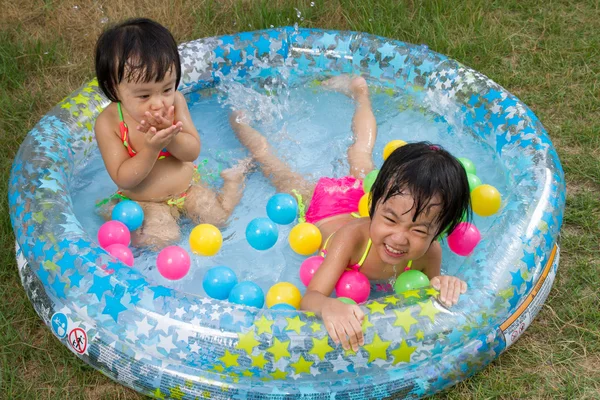 Asiática poco chino niñas jugando en un inflable goma nadando —  Fotos de Stock