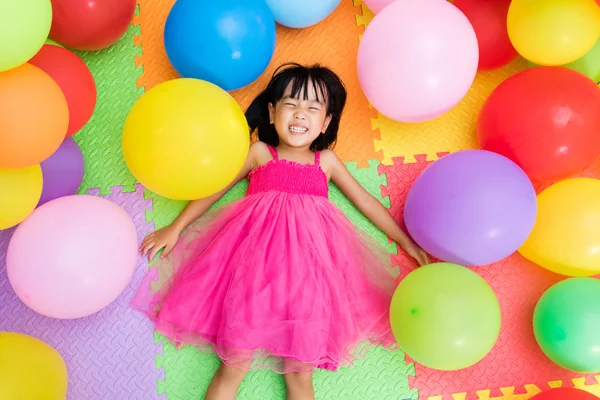 Asian Little Chinese Girl Lying on the Floor amongst Colorful Ba — Stock Photo, Image