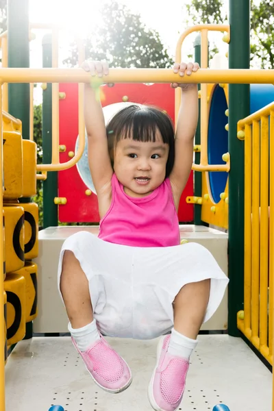 Asian little Chinese girl hanging on horizontal monkey bar — Stock Photo, Image