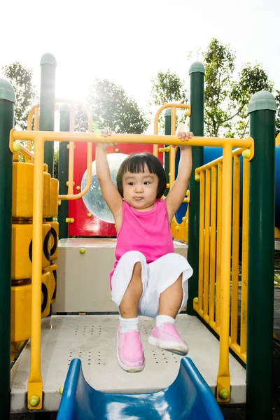Asian little Chinese girl hanging on horizontal monkey bar — Stock Photo, Image