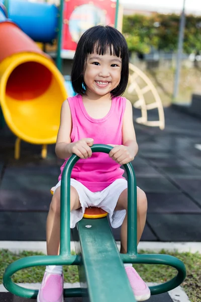 Aziatische Chinese meisje op wip op de speelplaats — Stockfoto