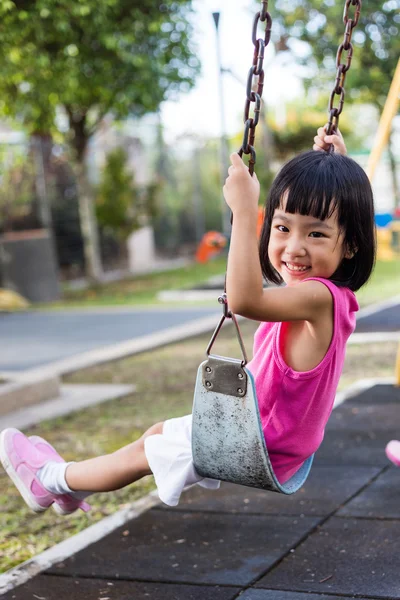 Asiatique chinois petite fille sur swing dans aire de jeux — Photo