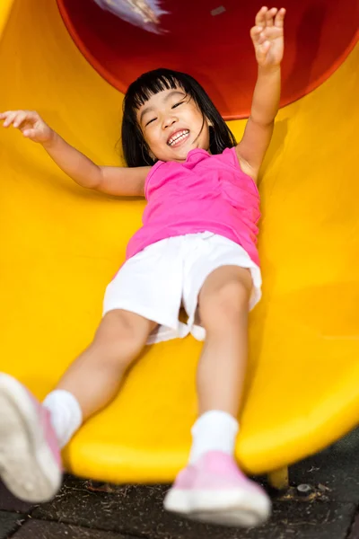 Asiática china niña deslizándose en el patio de recreo — Foto de Stock