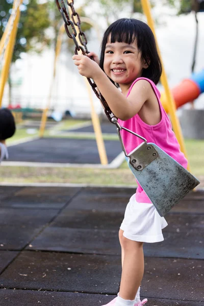 Asiatique chinois petite fille sur swing dans aire de jeux — Photo