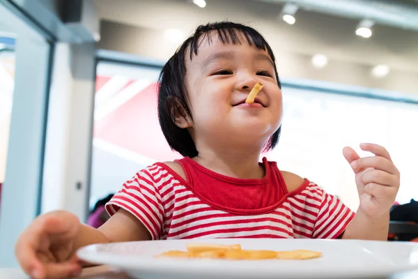 Asiatiska kinesiska lilla flicka äter pommes frites — Stockfoto