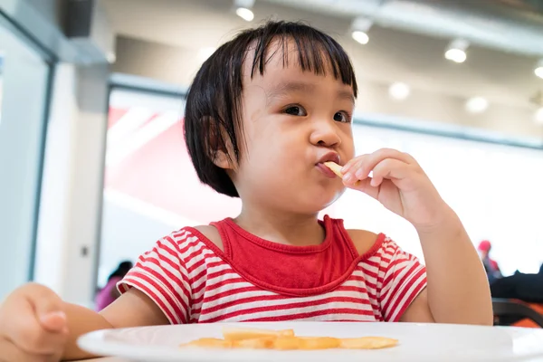 Asiatiska kinesiska lilla flicka äter pommes frites — Stockfoto