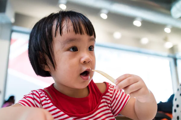 Asiatiska kinesiska lilla flicka äter pommes frites — Stockfoto