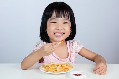 Mutlu Asyalı Çinli küçük kız yeme patates kızartması