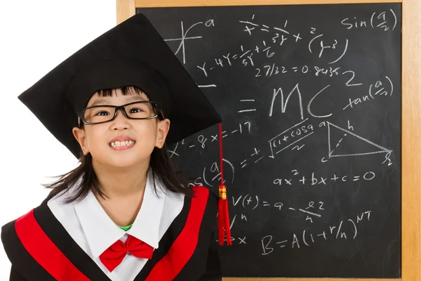 Asian Chinese little girl in graduation gown againts blackboard — Stock Photo, Image