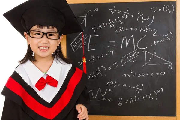 Asian Chinese little girl in graduation gown againts blackboard — Stock Photo, Image