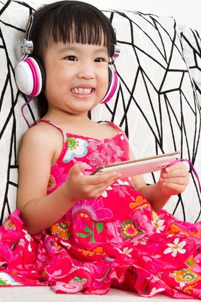 Çinli küçük kız cep telefonu tutan kulaklıklar üzerinde — Stok fotoğraf