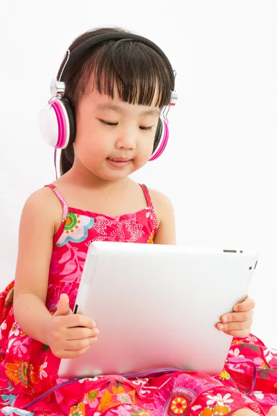 Chiński dziewczynka na słuchawki trzymając tabletkę — Zdjęcie stockowe