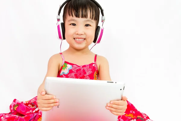 Çinli küçük kız tablet tutan kulaklıklar üzerinde — Stok fotoğraf