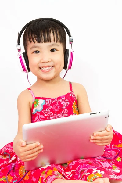 Çinli küçük kız tablet tutan kulaklıklar üzerinde — Stok fotoğraf