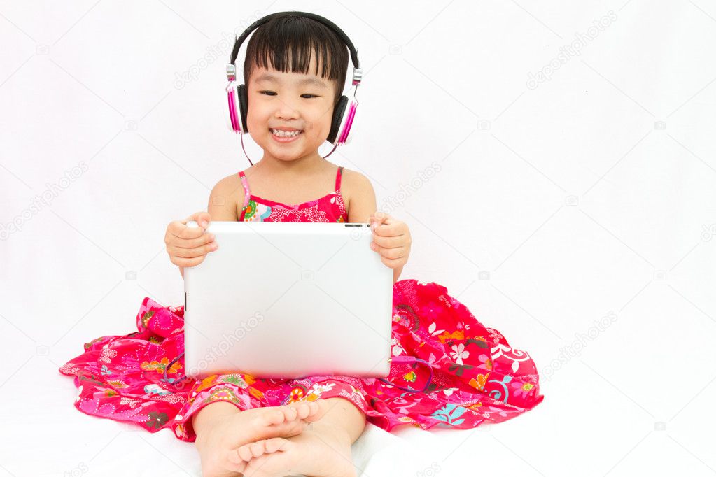 Chinese little girl on headphones holding tablet