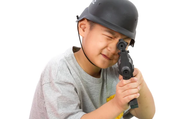 Азиатский мальчик играет в пластиковые игрушки AK47 с полицейским шлемом — стоковое фото