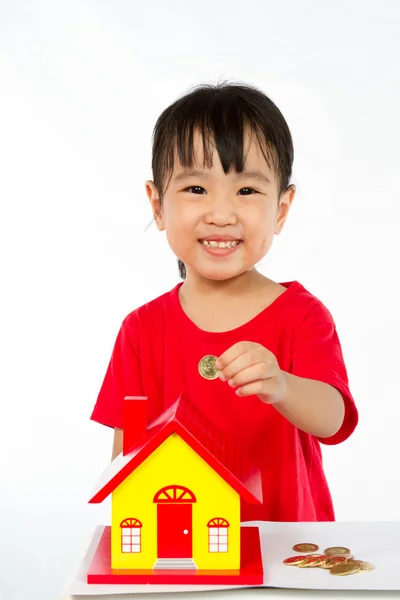 Chino niña pone monedas en alcancía — Foto de Stock
