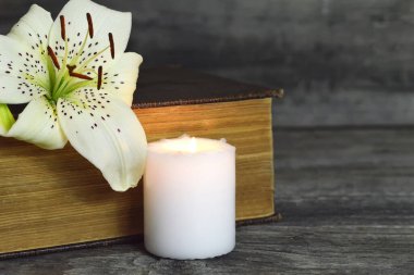 Beyaz mum, zambak çiçeği ve kapalı kitap. Kopya alanı ile başsağlığı kartı