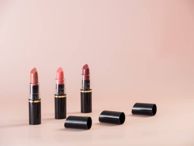 Pudralı arka planda kapakları olan farklı renklerde açık rujların yakın plan görüntüsü.