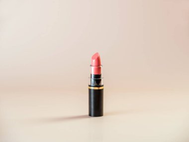 Yeni açık ruj pembeyle kaplanmış siyah ambalajlı pudralı arka planda. Yan görünüm