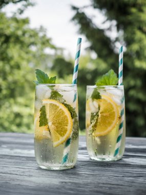Buzlu, limonlu ve şeffaf bir bardakta üzümlü soğuk karbonatlı limonata. Yaz içeceği bahçedeki ahşap bir masada duruyor. Arkaplan - köknar dalları