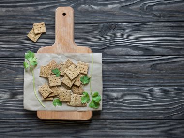 Tahta bir tahtada, koyu ahşap bir zeminde maydanozlu, düz, kare şeklinde çıtır çıtır çıtır çıtırlar. Düz yatıyordu. Beslenme yemekleri için lezzetli atıştırmalıklar.