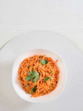 Baharatlı Asya salatası, rendelenmiş havuç ve maydanoz. Siyah arka planda, sade, yemek çubukları ve tekstil ile siyah bir kâsede Kore havuçları. Vejetaryen diyeti. Sağlıklı gıda konsepti. Yukarıdan görüntüle