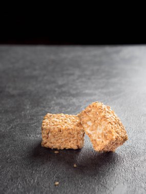 Gri arka planda susam tohumları bulunan geleneksel sütlü tatlı oryantal Türk lokumu (rahat locum). Yan görüş. Boşluğu kopyala.