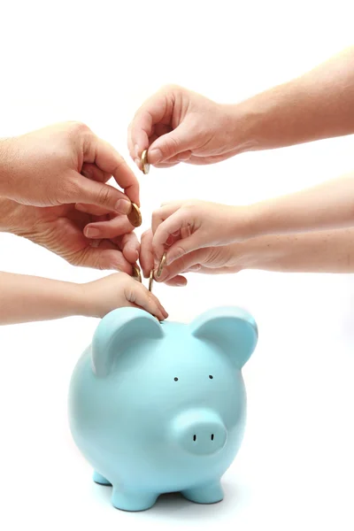 Hands putting coins into piggy bank — Stock Photo, Image