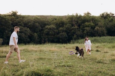 Amerikan Akita köpeği yeşil çayırda bir adam ve bir kızla yürüyüşe çıktı.