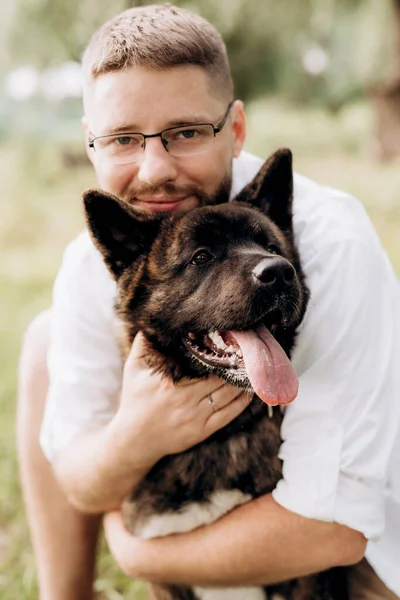 Amerikan Akita köpeği yeşil çayırda bir adam ve bir kızla yürüyüşe çıktı.