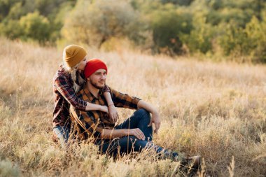 Neşeli adam ve kız parlak örgü şapkalar ve ekose gömleklerle yürüyüşe çıktılar.