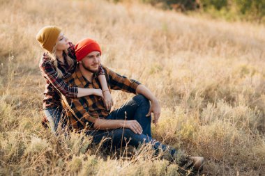 Neşeli adam ve kız parlak örgü şapkalar ve ekose gömleklerle yürüyüşe çıktılar.