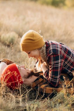 Neşeli adam ve kız parlak örgü şapkalar ve ekose gömleklerle yürüyüşe çıktılar.