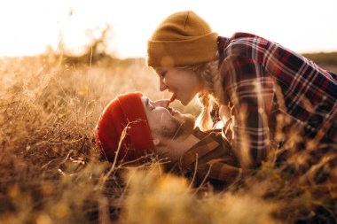 Neşeli adam ve kız parlak örgü şapkalar ve ekose gömleklerle yürüyüşe çıktılar.
