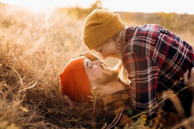 Neşeli adam ve kız parlak örgü şapkalar ve ekose gömleklerle yürüyüşe çıktılar.