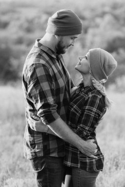 Neşeli adam ve kız parlak örgü şapkalar ve ekose gömleklerle yürüyüşe çıktılar.