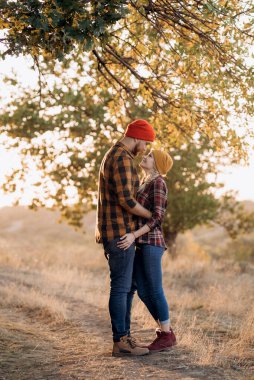 Neşeli adam ve kız parlak örgü şapkalar ve ekose gömleklerle yürüyüşe çıktılar.