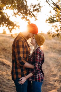 Neşeli adam ve kız parlak örgü şapkalar ve ekose gömleklerle yürüyüşe çıktılar.