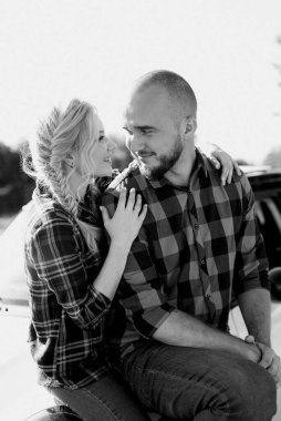 Kareli gömlekli bir kız ve genç bir adamın arabasıyla seyahat ediyor.