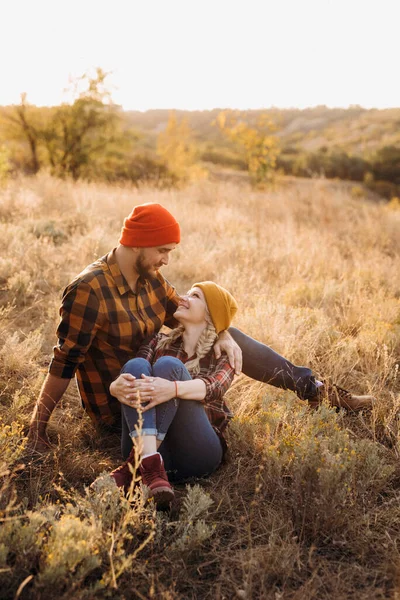 Neşeli adam ve kız parlak örgü şapkalar ve ekose gömleklerle yürüyüşe çıktılar.