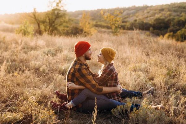 Neşeli adam ve kız parlak örgü şapkalar ve ekose gömleklerle yürüyüşe çıktılar.