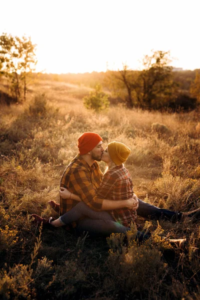 Neşeli adam ve kız parlak örgü şapkalar ve ekose gömleklerle yürüyüşe çıktılar.