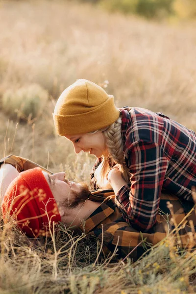 Neşeli adam ve kız parlak örgü şapkalar ve ekose gömleklerle yürüyüşe çıktılar.