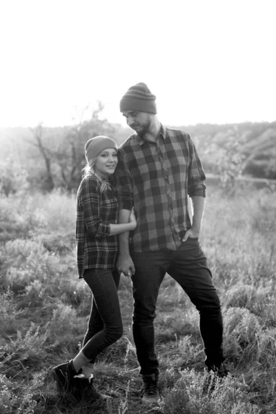 Neşeli adam ve kız parlak örgü şapkalar ve ekose gömleklerle yürüyüşe çıktılar.