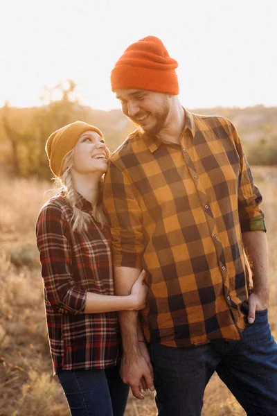 Neşeli adam ve kız parlak örgü şapkalar ve ekose gömleklerle yürüyüşe çıktılar.