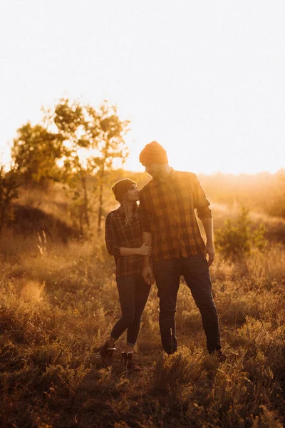Neşeli adam ve kız parlak örgü şapkalar ve ekose gömleklerle yürüyüşe çıktılar.